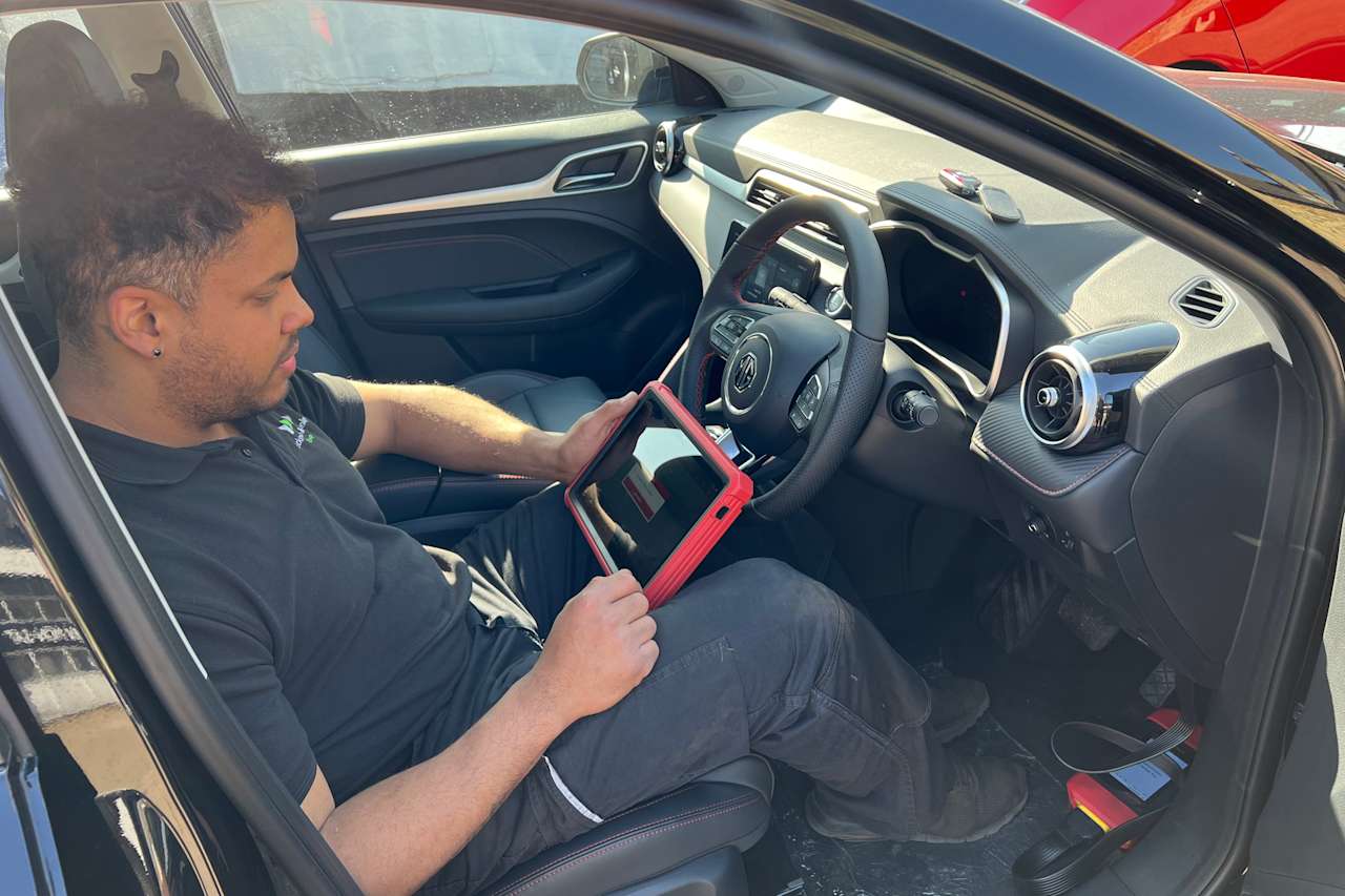 Cambridge EV technician sat in an EV with a computer carrying out an EV service