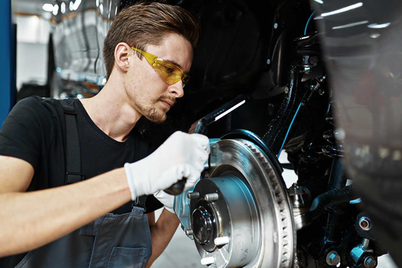 Technician replacing a brake disc with the tyre removed