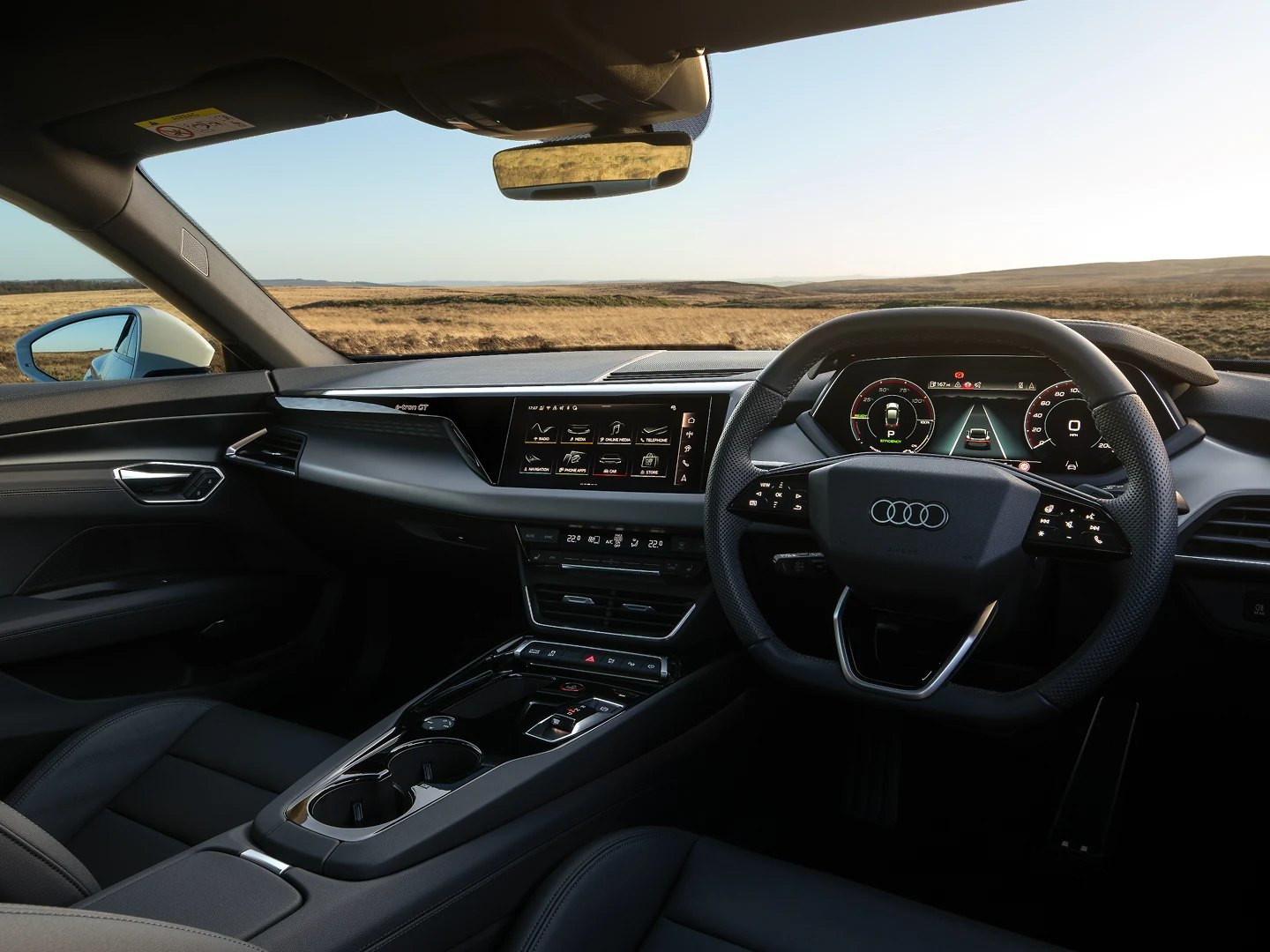 Audi interior with steering wheel and digital displays overlooking open countryside