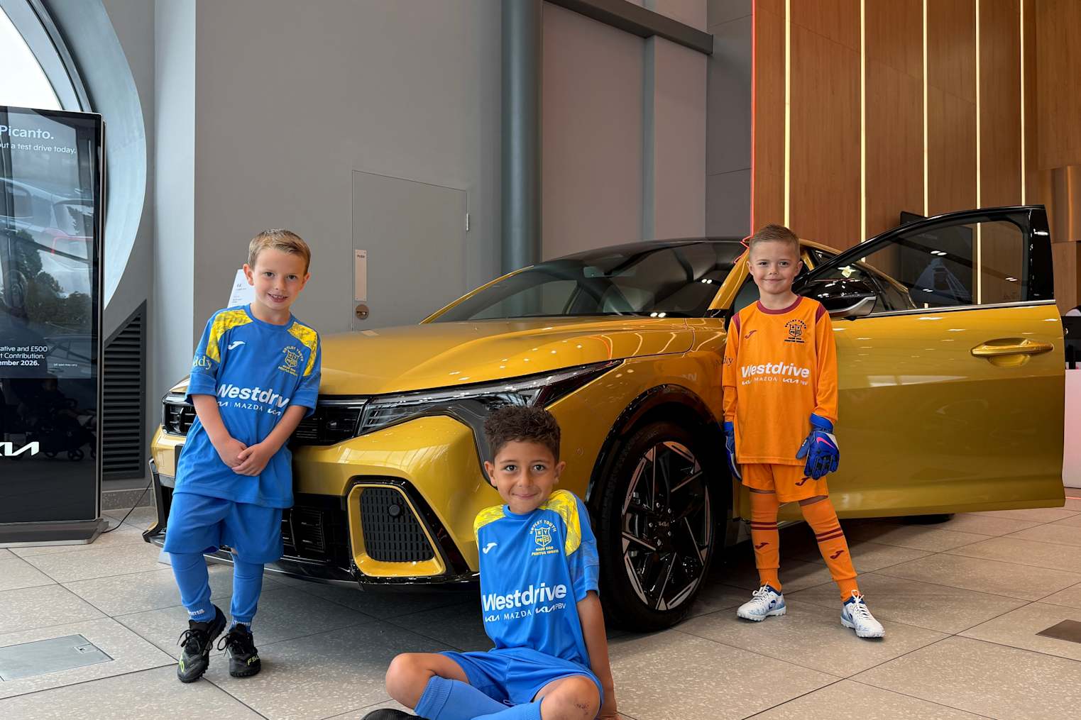 Notley Youth FC Under 8s Kestrels in their new kit posing in front of Kia cars at Westdrive Kia Braintree