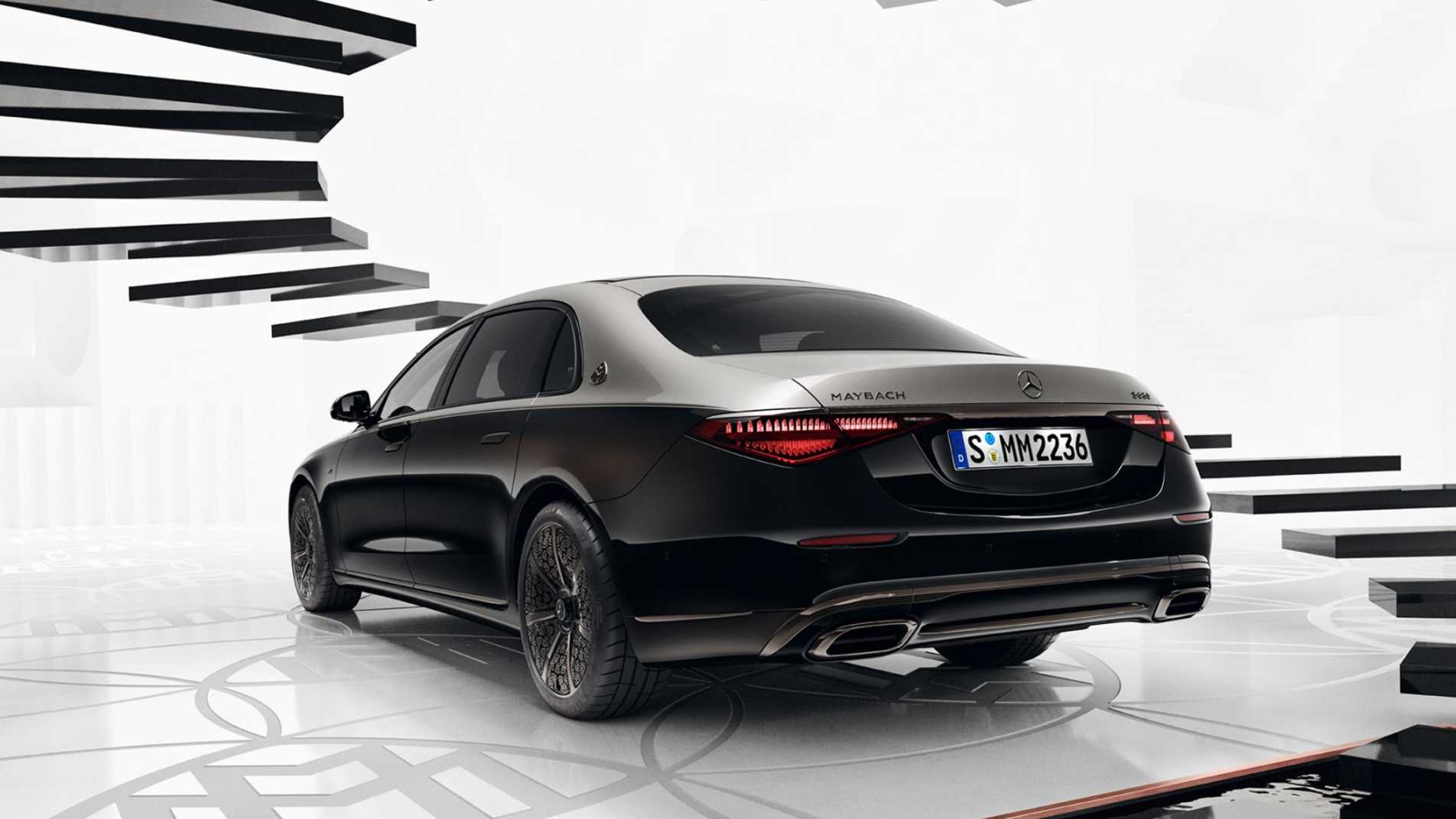 Black Mercedes-Maybach S-Class Night Series sedan on a reflective platform with sculptural black beams overhead