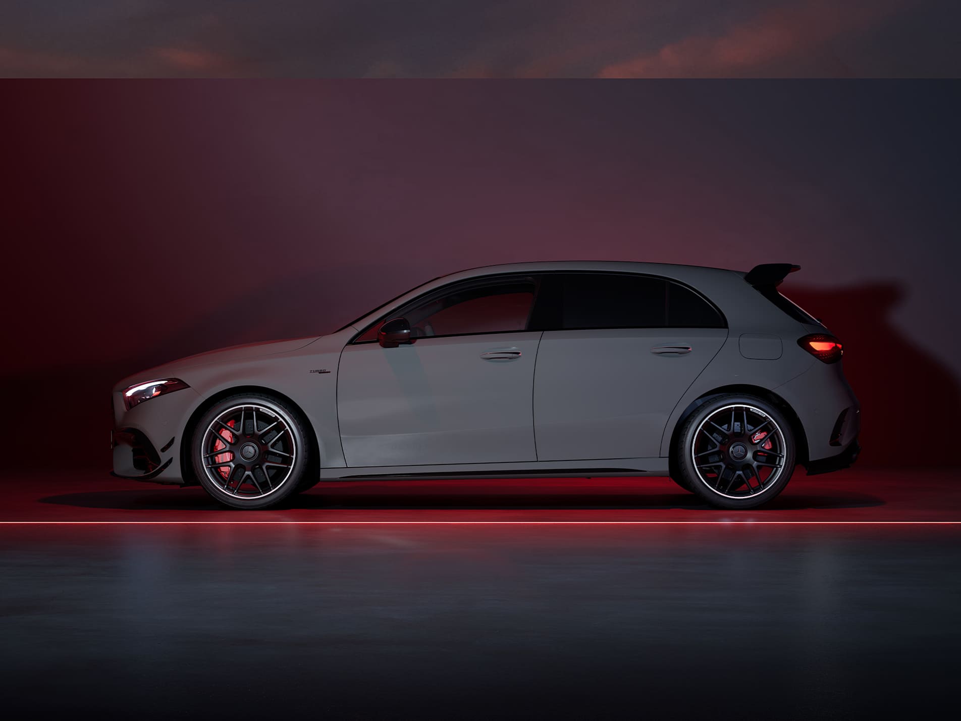Grey Mercedes-AMG A-Class hatchback side view against a dark red backdrop