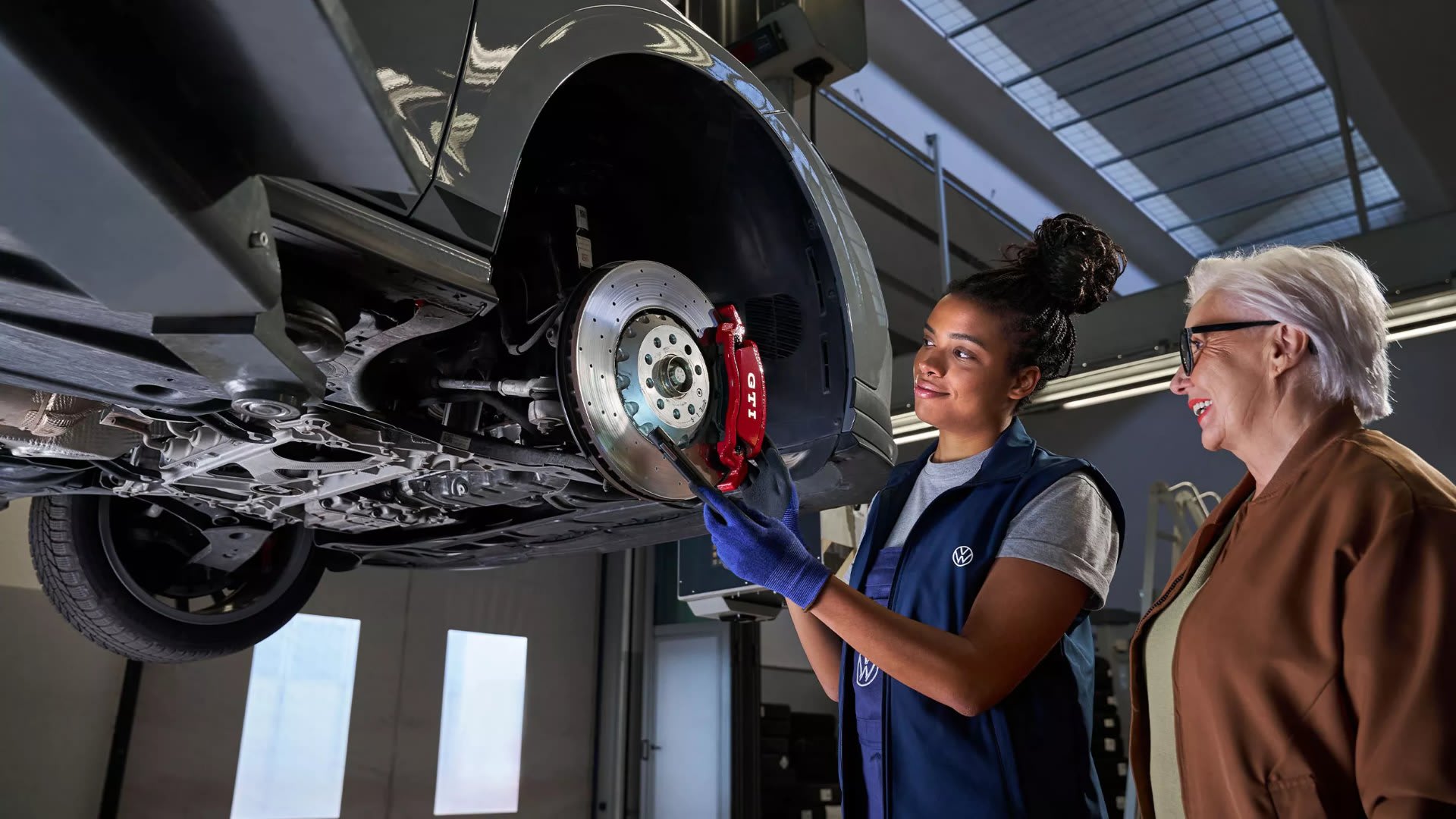 Volkswagen technician with a customer looking at the brakes of their car – brake repairs at Camerons Volkswagen, Perth