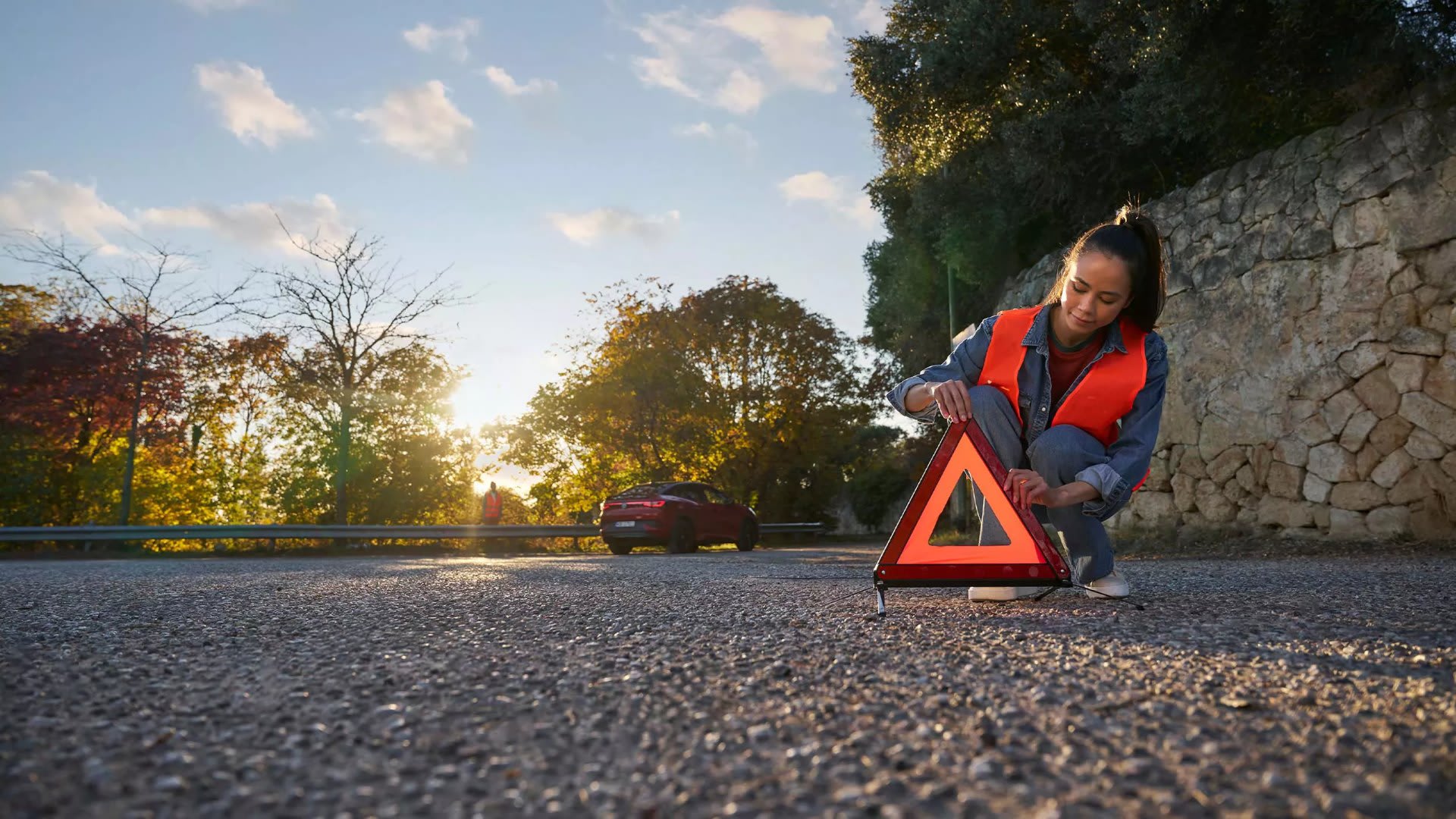 Driver in a high-vis vest setting up a warning triangle beside a Volkswagen ID.5 – roadside assistance from Camerons Volkswagen, Perth