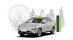 A grey car plugged into an electric vehicle charger.In the background there is a skyline of London