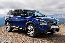 A blue New Nissan X-Trail SUV parked on a rocky terrain with a mountainous landscape in the background