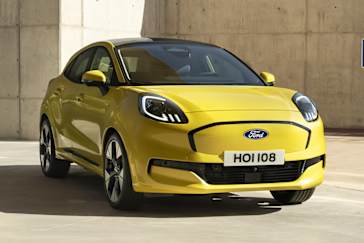 A bright yellow Ford New All-Electric Puma Gen-E parked in a modern setting with a concrete background