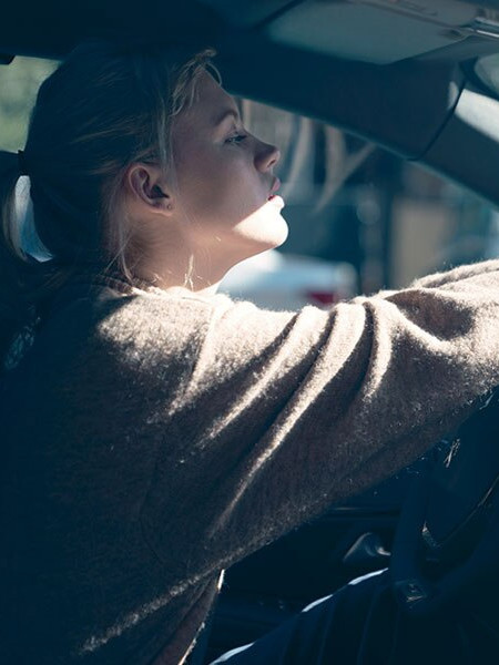 Blonde woman driving a Peugeot 208