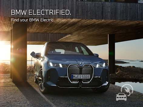 BMW iX charging at a modern luxury home during sunset