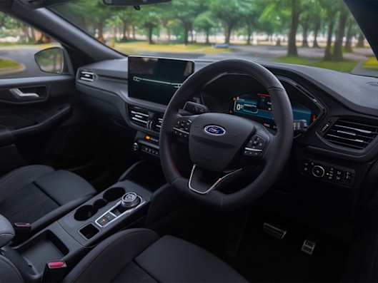 Interior view of a modern Ford Kuga, featuring a steering wheel, dashboard, and touchscreen display.