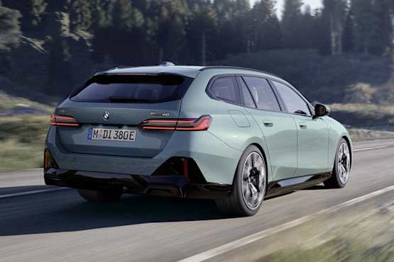 A sleek Cape York Green BMW i5 Touring M Sport Electric car in a rural setting with trees