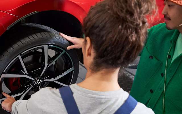 Volkswagen technician pointing at a wheel with a customer – tyre checks at Camerons Volkswagen, Perth