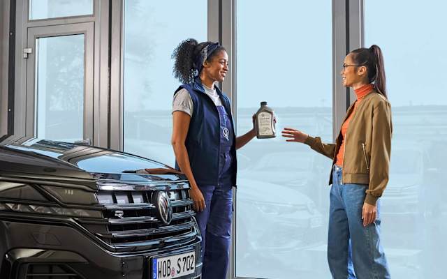 Volkswagen service adviser handing a customer a bottle of Volkswagen Genuine engine oil – Camerons Volkswagen, Perth