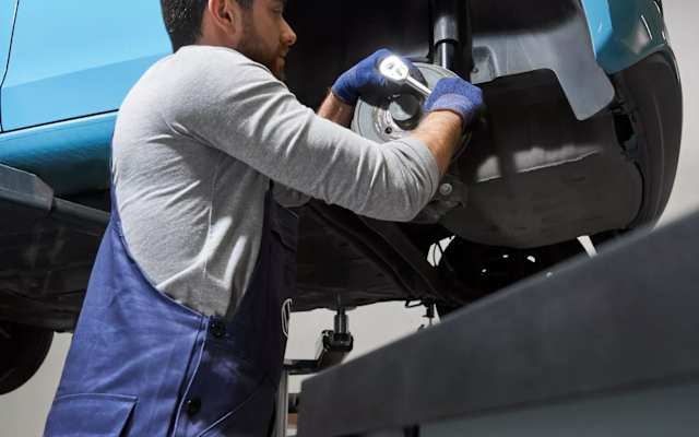 Technician working underneath a Volkswagen on a ramp – fixed price servicing at Camerons Volkswagen, Perth