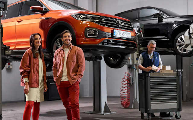 Couple in a Volkswagen workshop with two cars on ramps – repairs and checks at Camerons Volkswagen, Perth