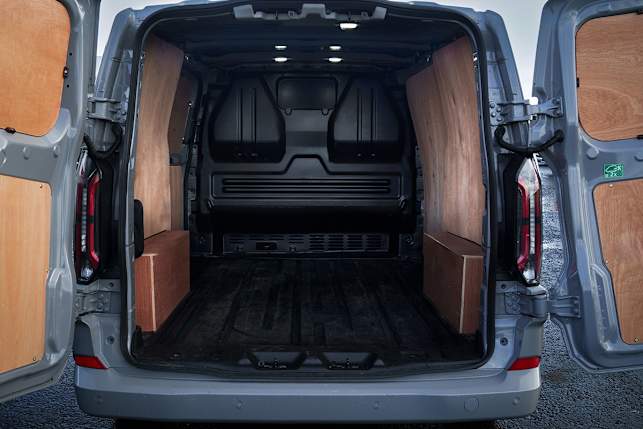 Interior of a Ford E-Transit Custom van showing wooden panels and a spacious cargo area with open doors.