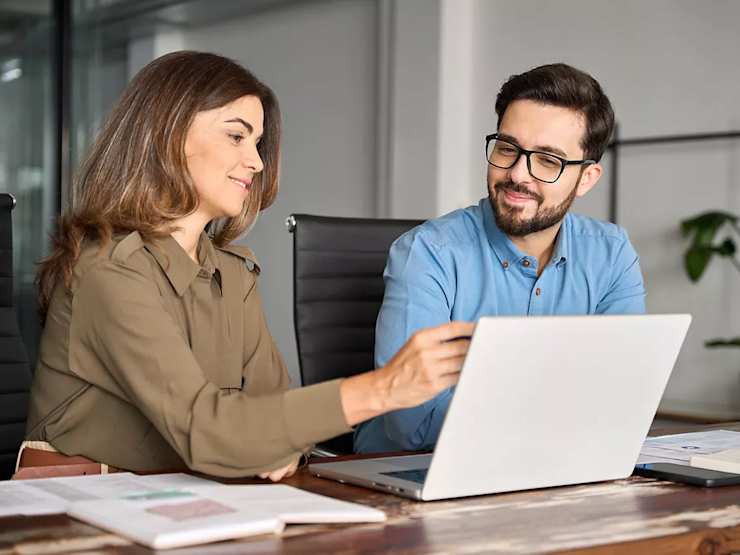 Man and Woman talking, looking at laptop