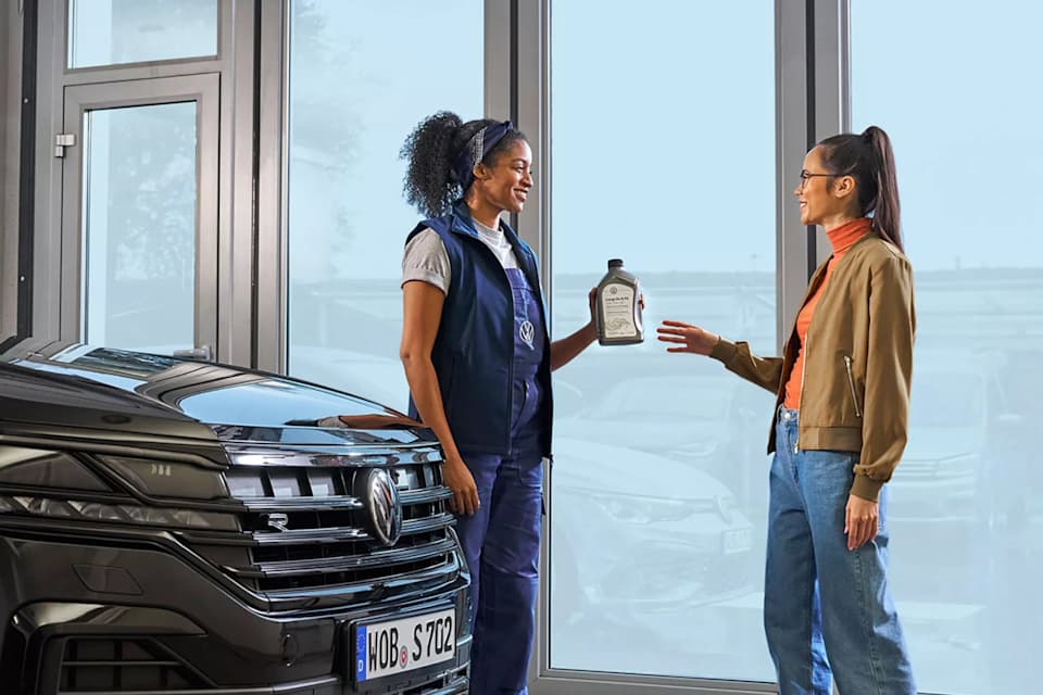 Volkswagen service adviser handing a customer a bottle of Volkswagen Genuine engine oil – Camerons Volkswagen, Perth
