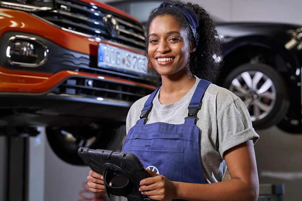Volkswagen technician with a tablet, T-Cross and Touareg on ramps behind – vehicle checks at Camerons Volkswagen, Perth